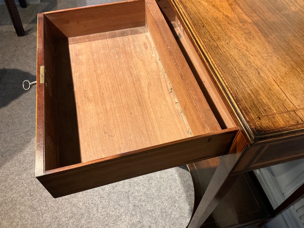 A late Georgian Sheraton mahogany work table featuring satinwood crossbanding, a single drawer, tapered square legs, and a concave lower undertier. View XII