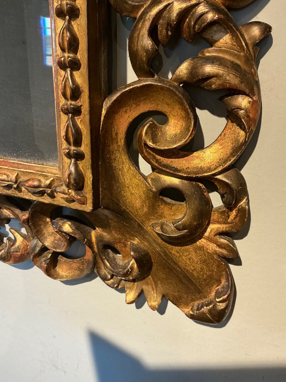 A rectangular antique wall mirror featuring a heavily carved and pierced giltwood frame decorated with acanthus leaf motifs and scrollwork. View II