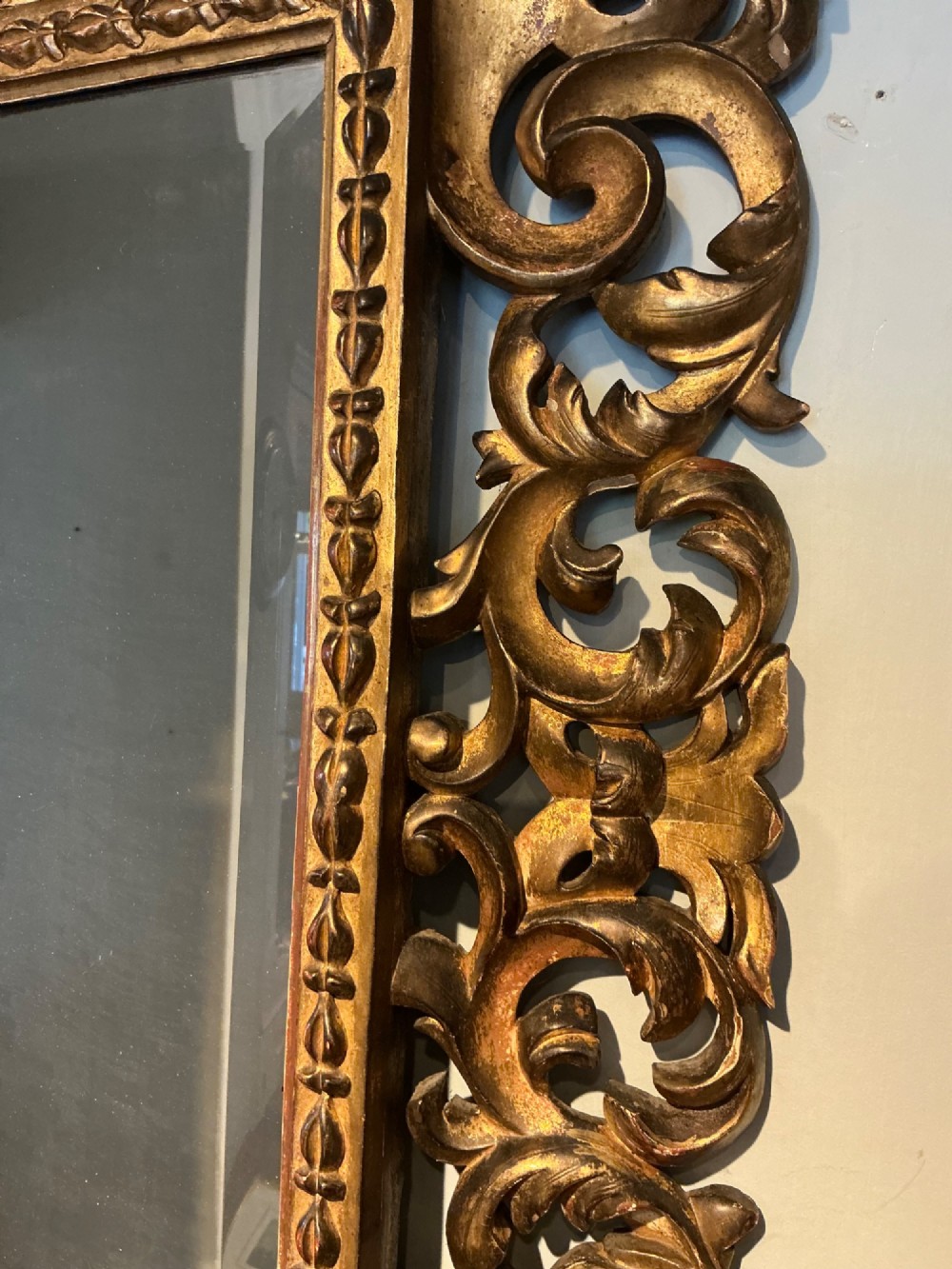 A rectangular antique wall mirror featuring a heavily carved and pierced giltwood frame decorated with acanthus leaf motifs and scrollwork. View III