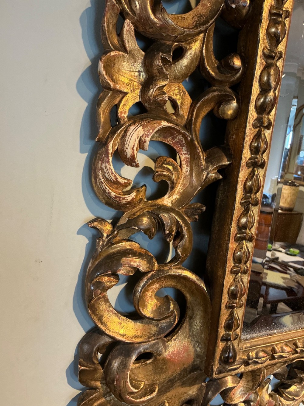 A rectangular antique wall mirror featuring a heavily carved and pierced giltwood frame decorated with acanthus leaf motifs and scrollwork. View IV