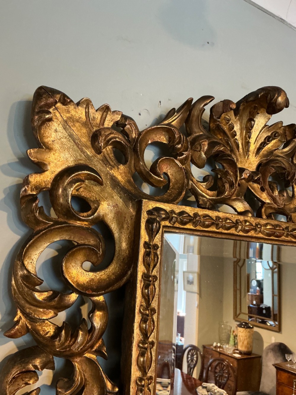 A rectangular antique wall mirror featuring a heavily carved and pierced giltwood frame decorated with acanthus leaf motifs and scrollwork. View V