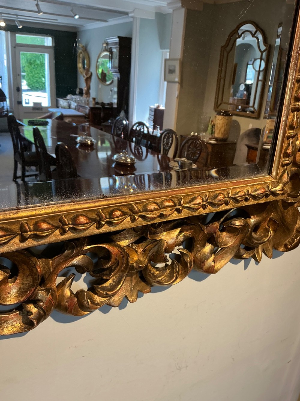 A rectangular antique wall mirror featuring a heavily carved and pierced giltwood frame decorated with acanthus leaf motifs and scrollwork. View VII