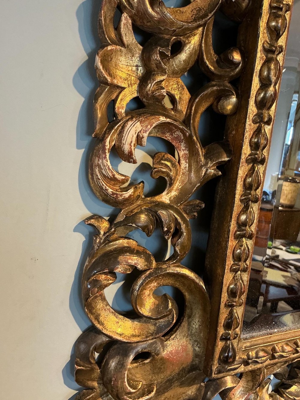 A rectangular antique wall mirror featuring a heavily carved and pierced giltwood frame decorated with acanthus leaf motifs and scrollwork. View VIII