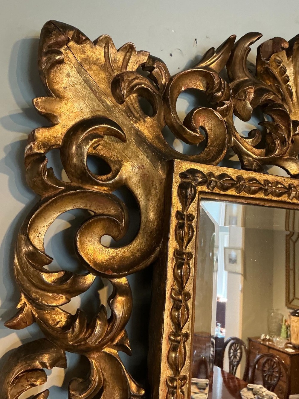 A rectangular antique wall mirror featuring a heavily carved and pierced giltwood frame decorated with acanthus leaf motifs and scrollwork. View IX