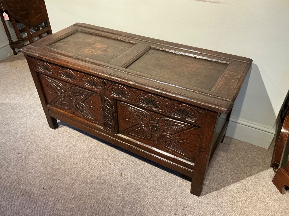 A dark oak coffer featuring hand-carved floral panels and a hinged two-panel top lid. View III