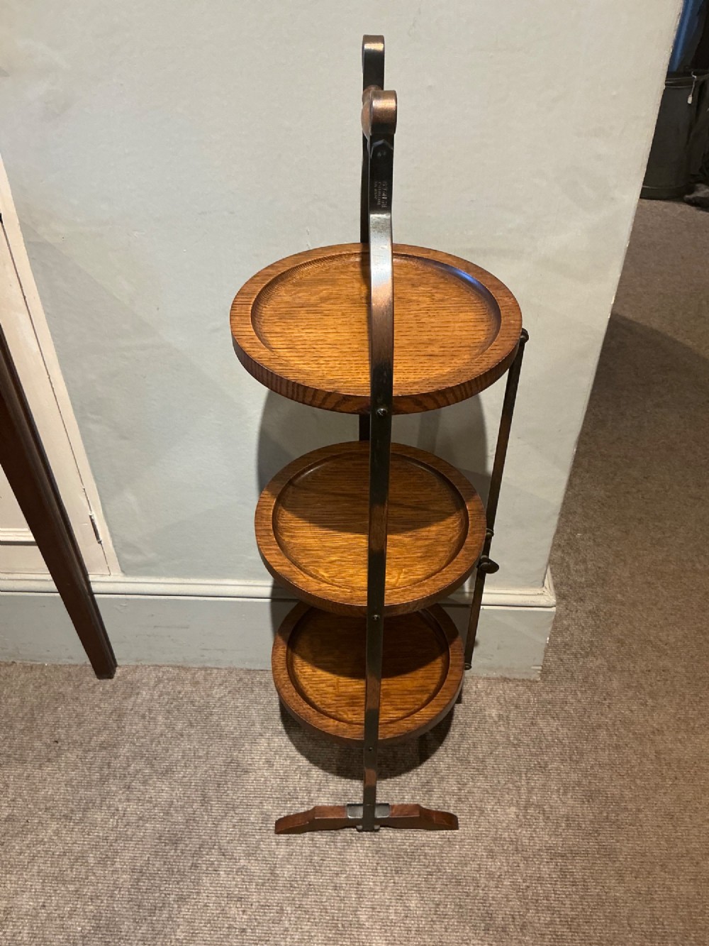 An antique three-tier folding oak cake stand featuring a central turned wooden handle and a dark metal frame. View IV