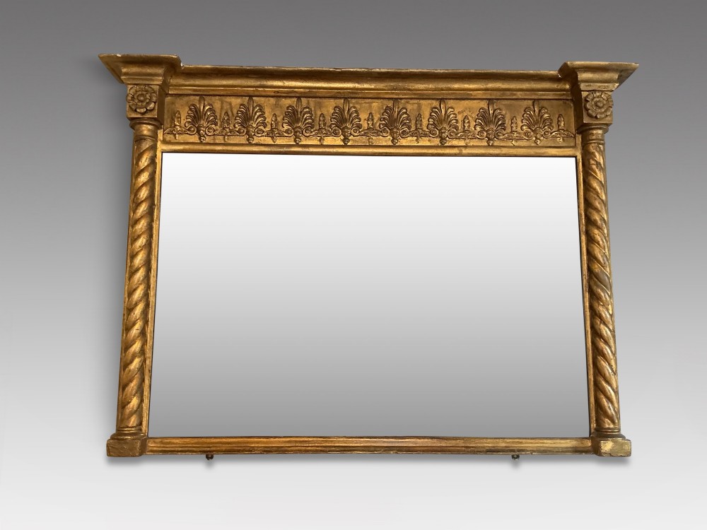 A horizontal Regency giltwood overmantel mirror featuring an anthemion frieze across the top and spiral-twist side columns.