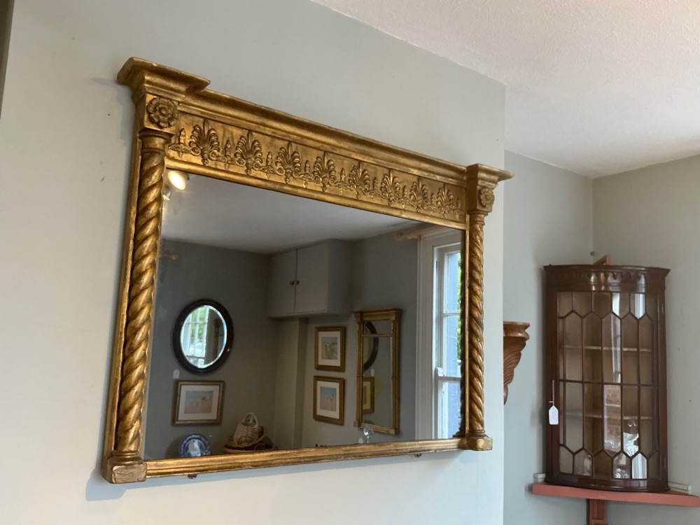 A horizontal Regency giltwood overmantel mirror featuring an anthemion frieze across the top and spiral-twist side columns. View II