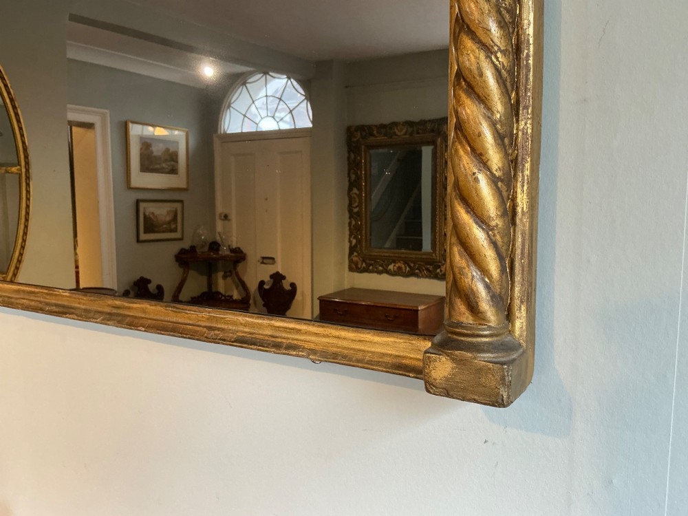 A horizontal Regency giltwood overmantel mirror featuring an anthemion frieze across the top and spiral-twist side columns. View V