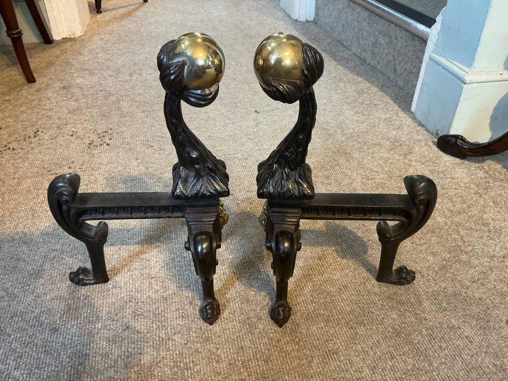 A pair of antique cast iron and brass andirons featuring spherical brass finials, lion mask central motifs, scrolled legs, and claw feet. View III