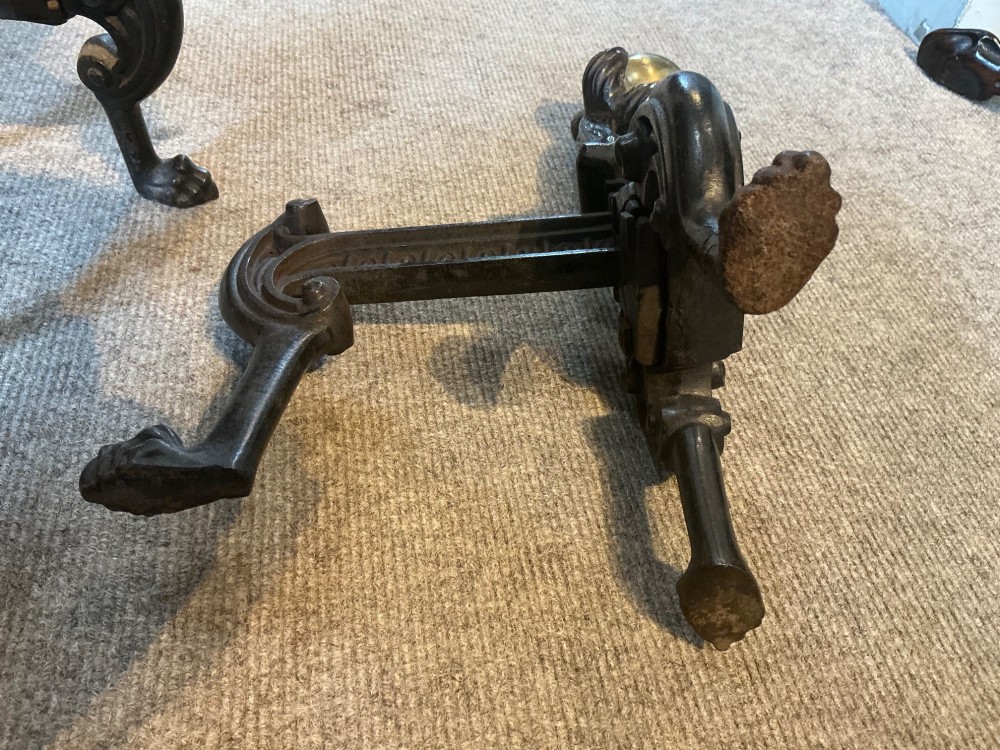 A pair of antique cast iron and brass andirons featuring spherical brass finials, lion mask central motifs, scrolled legs, and claw feet. View V