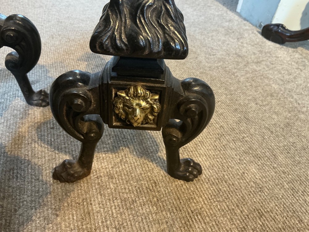 A pair of antique cast iron and brass andirons featuring spherical brass finials, lion mask central motifs, scrolled legs, and claw feet. View VI