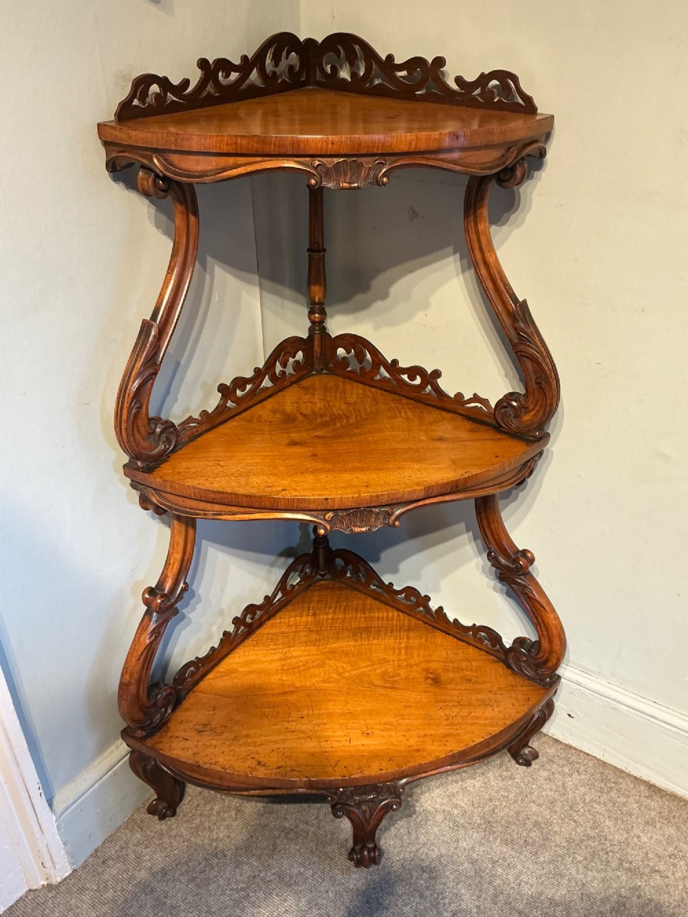 A three-tier antique corner whatnot in warm brown polished wood, featuring pierced fretwork galleries, serpentine supports, and carved feet. View II