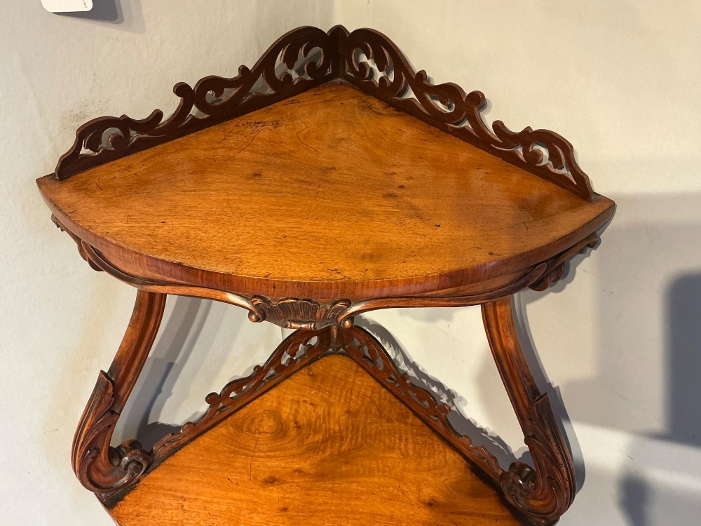 A three-tier antique corner whatnot in warm brown polished wood, featuring pierced fretwork galleries, serpentine supports, and carved feet. View III
