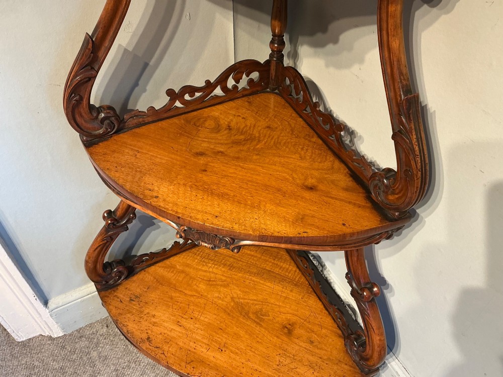 A three-tier antique corner whatnot in warm brown polished wood, featuring pierced fretwork galleries, serpentine supports, and carved feet. View IV