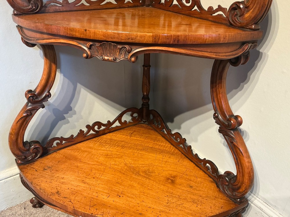 A three-tier antique corner whatnot in warm brown polished wood, featuring pierced fretwork galleries, serpentine supports, and carved feet. View VI