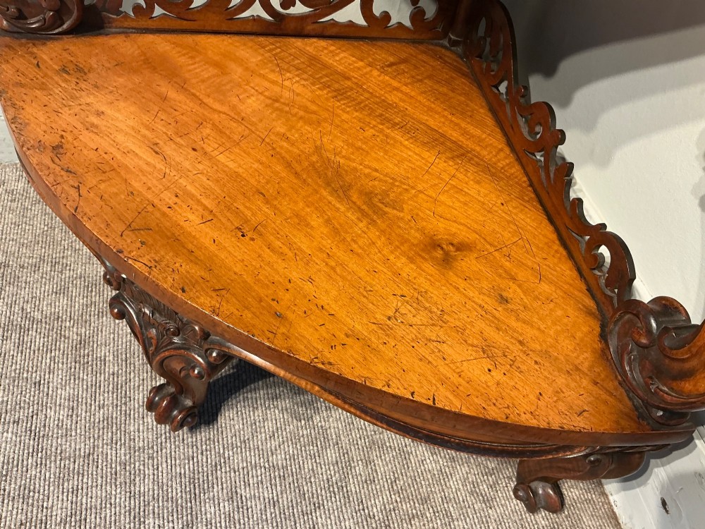 A three-tier antique corner whatnot in warm brown polished wood, featuring pierced fretwork galleries, serpentine supports, and carved feet. View VII