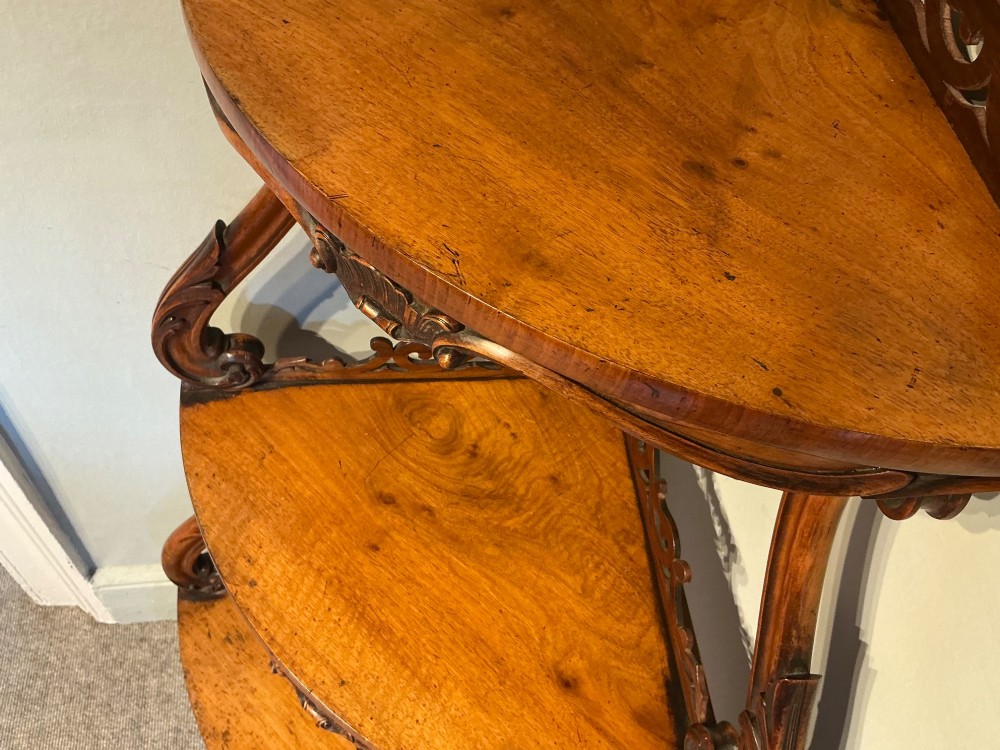A three-tier antique corner whatnot in warm brown polished wood, featuring pierced fretwork galleries, serpentine supports, and carved feet. View VIII