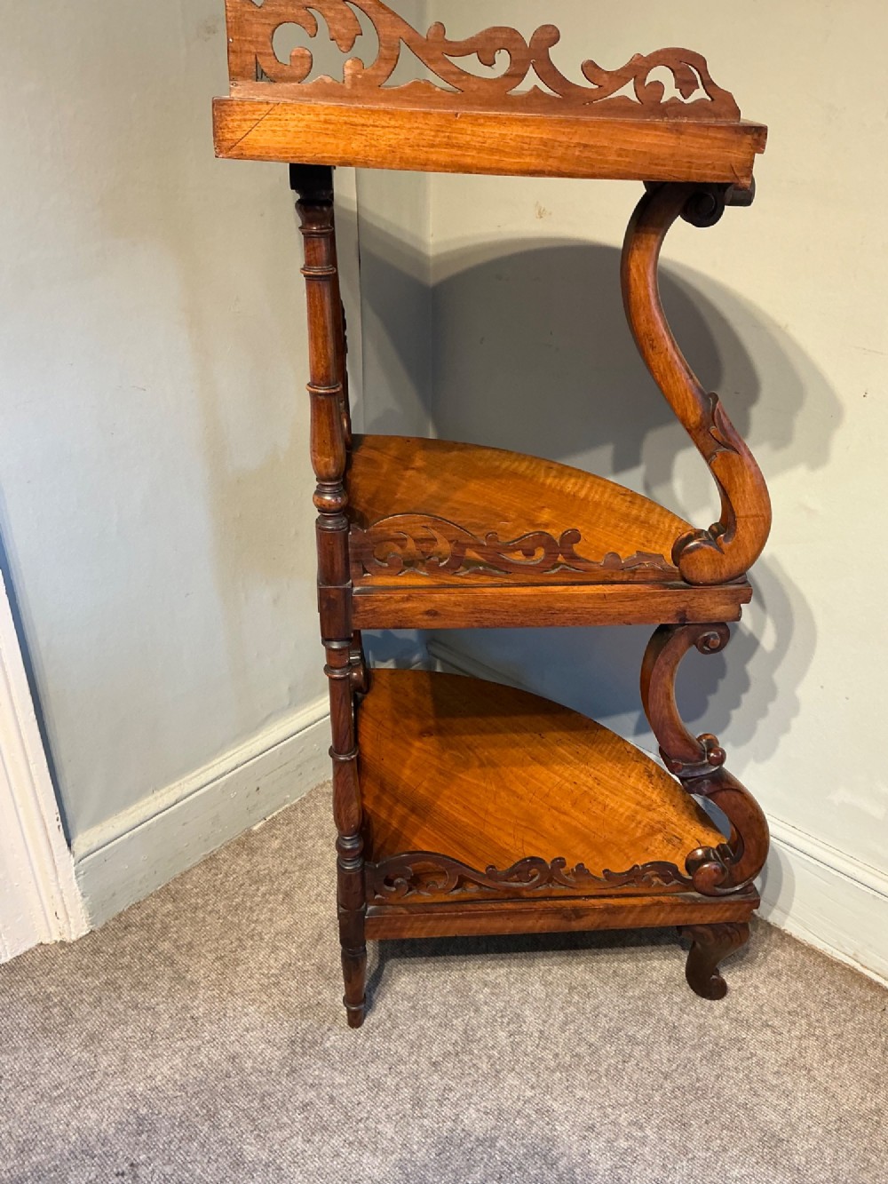 A three-tier antique corner whatnot in warm brown polished wood, featuring pierced fretwork galleries, serpentine supports, and carved feet. View IX