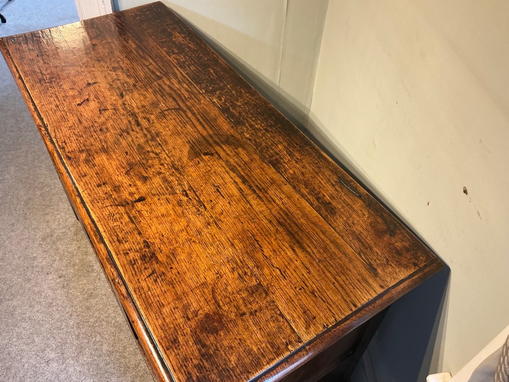 A carved oak coffer featuring three carved front panels with stylised leaf motifs, a carved top frieze, an iron keyhole, and sturdy stile legs. View III