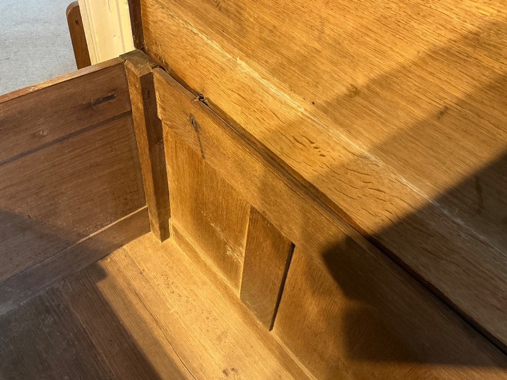 A carved oak coffer featuring three carved front panels with stylised leaf motifs, a carved top frieze, an iron keyhole, and sturdy stile legs. View VI