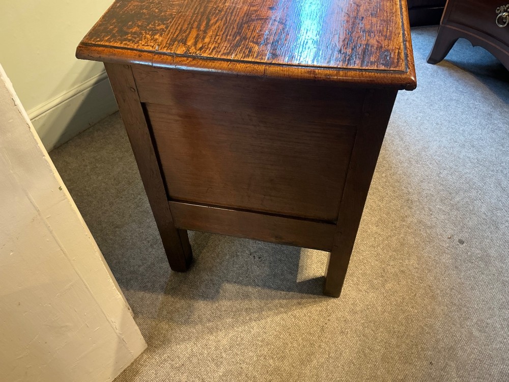 A carved oak coffer featuring three carved front panels with stylised leaf motifs, a carved top frieze, an iron keyhole, and sturdy stile legs. View IX