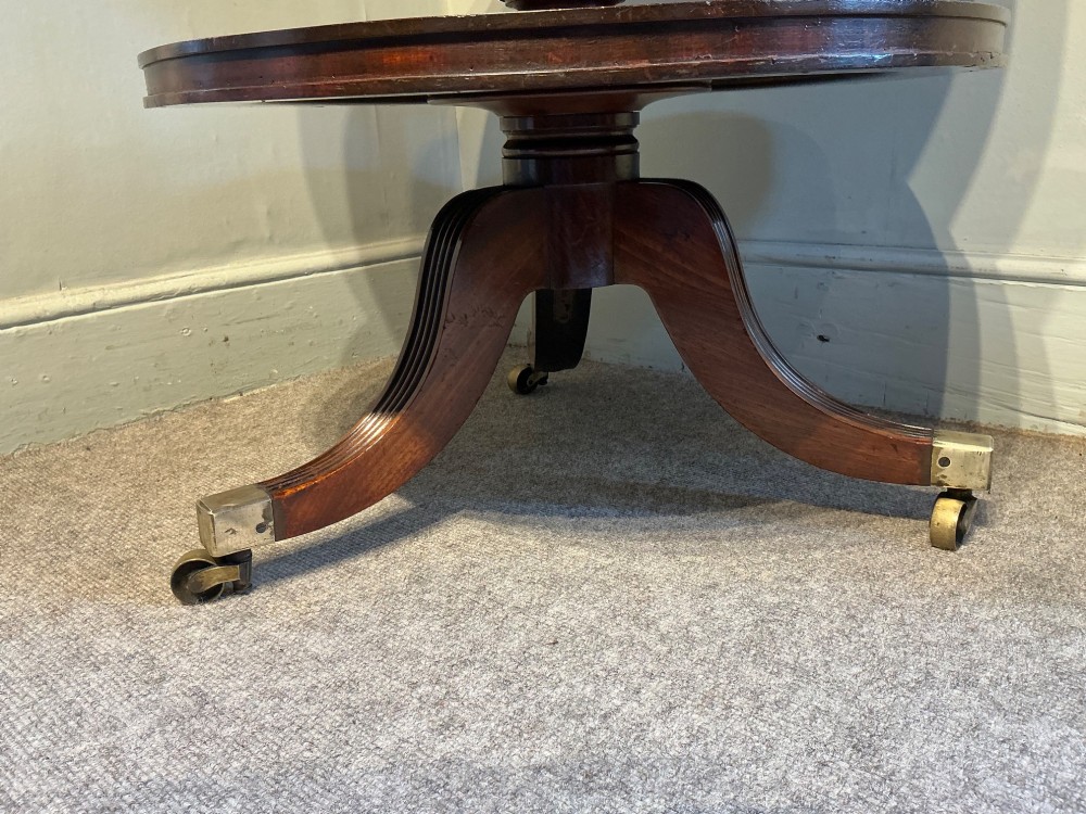 A two-tier dark mahogany Regency dumb waiter featuring a turned central column, reeded tripod legs, and brass castors. View IV