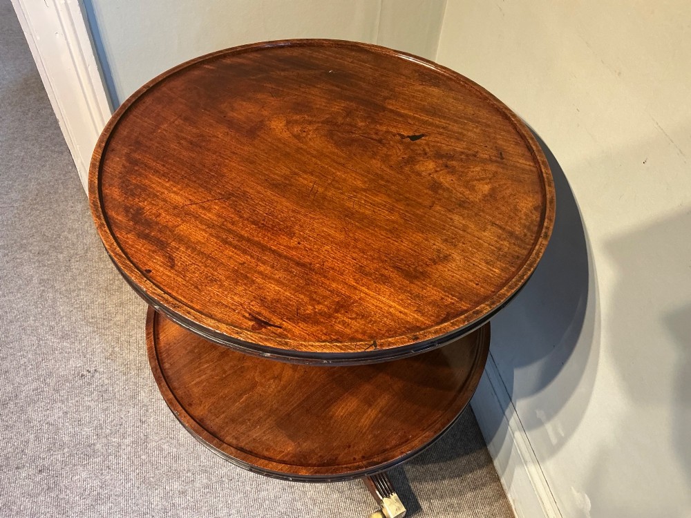 A two-tier dark mahogany Regency dumb waiter featuring a turned central column, reeded tripod legs, and brass castors. View VIII
