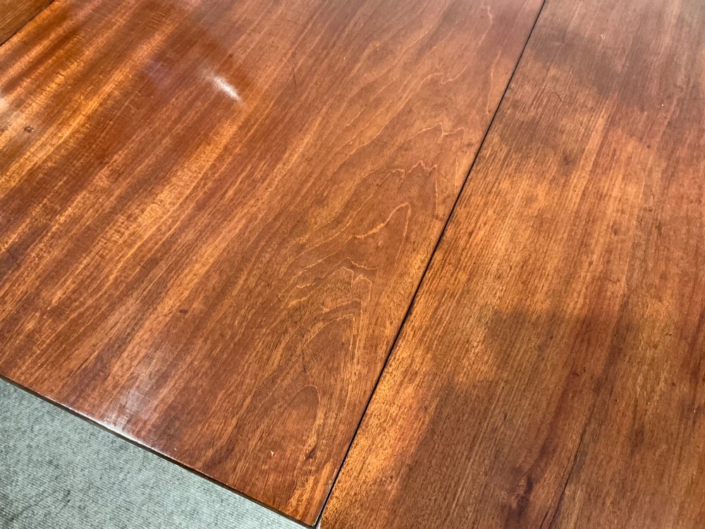An antique mahogany twin pedestal dining table with rounded corners, extending leaves, turned supports, and splayed legs with brass castors. View XII