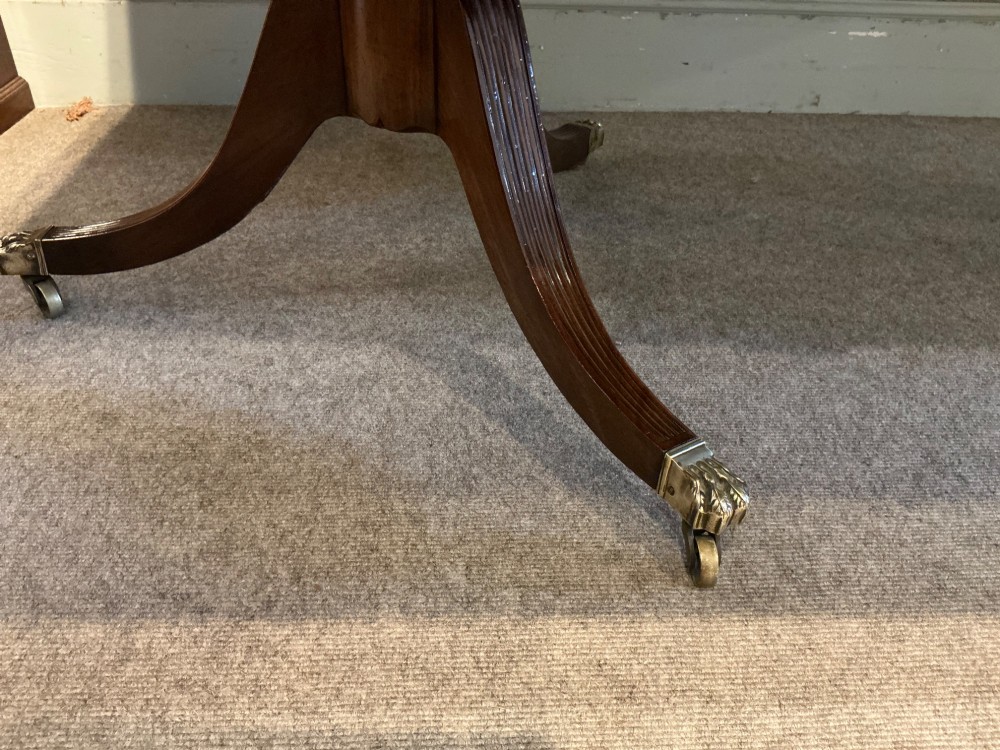 An antique mahogany twin pedestal dining table with rounded corners, extending leaves, turned supports, and splayed legs with brass castors. View XV