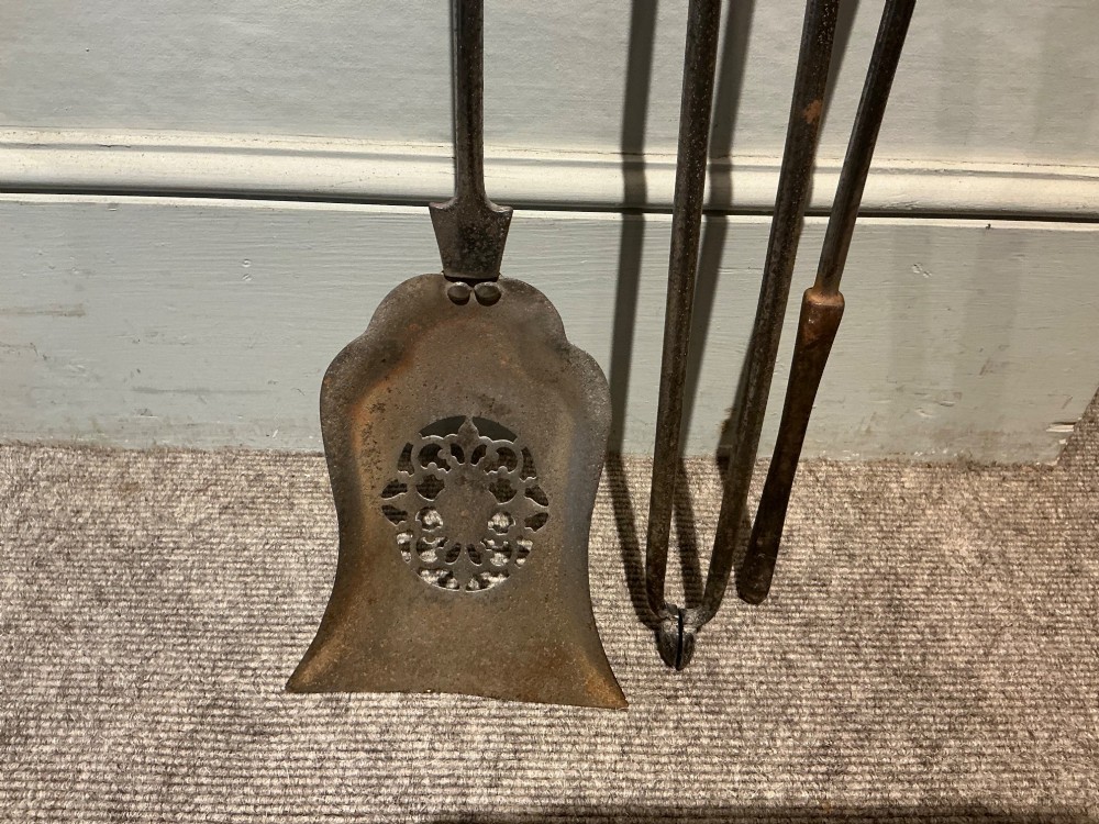 A three-piece set of polished steel fire tools including tongs, a poker, and a shovel with a pierced decorative blade. View V