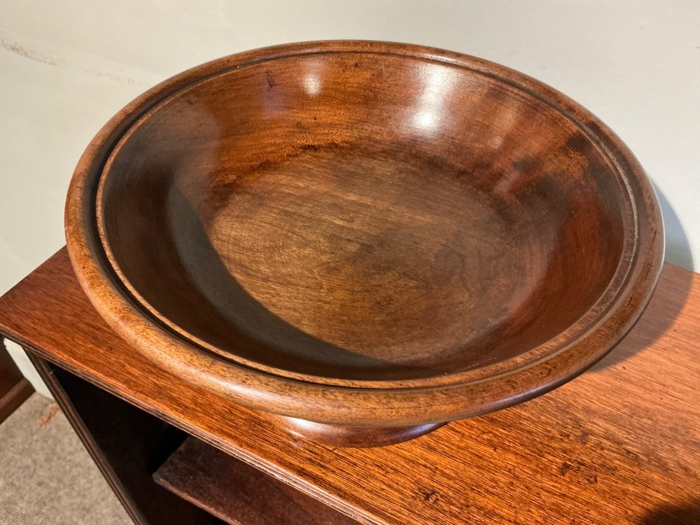 A turned wooden antique treen pedestal bowl with a polished finish and stepped circular base. View II