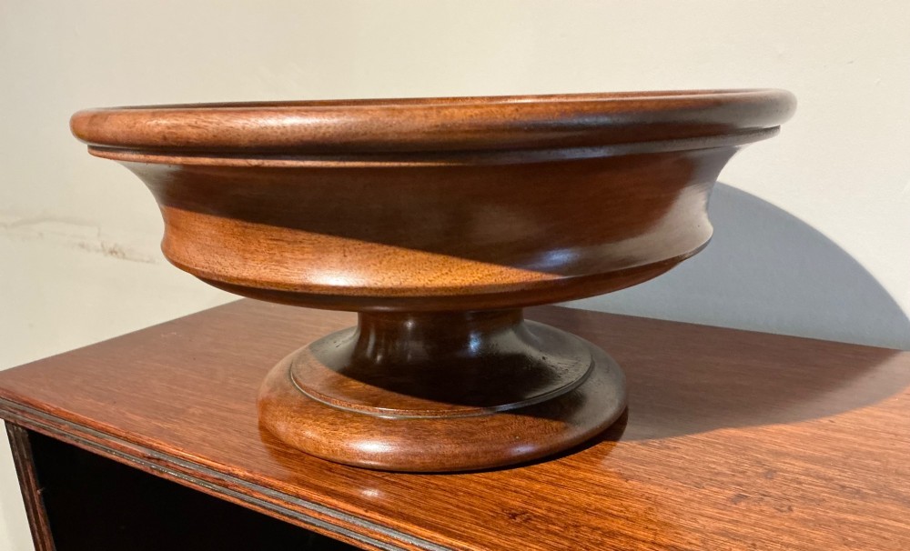 A turned wooden antique treen pedestal bowl with a polished finish and stepped circular base. View III