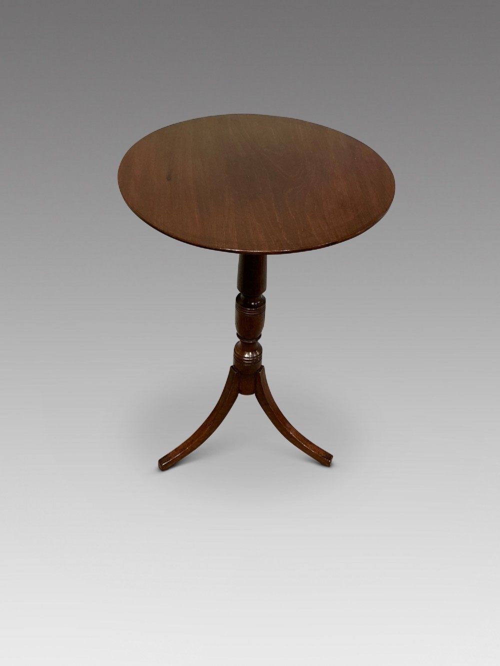 An antique dark mahogany wine table featuring a circular top supported by a turned central column on a tripod base.