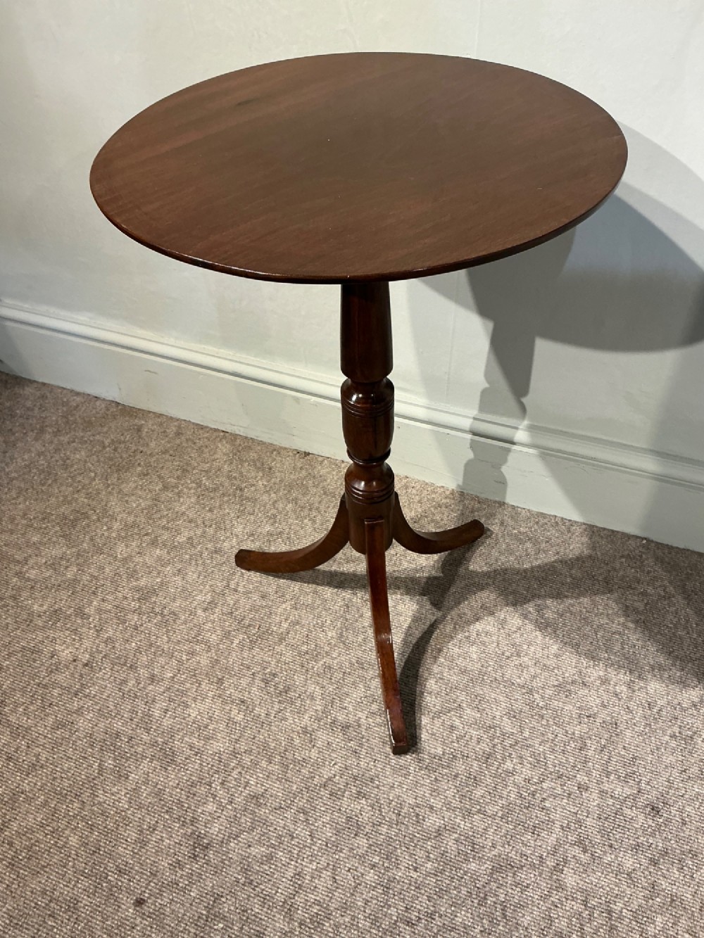 An antique dark mahogany wine table featuring a circular top supported by a turned central column on a tripod base. View II