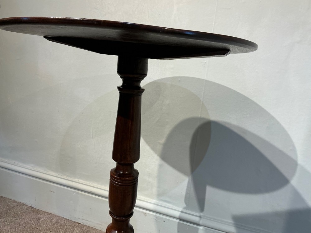 An antique dark mahogany wine table featuring a circular top supported by a turned central column on a tripod base. View VII