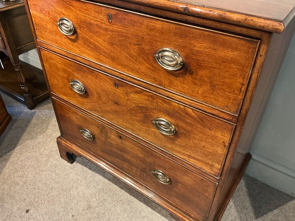 A Georgian mahogany chest of drawers with three graduated drawers, oval brass drop handles, and bracket feet. View III