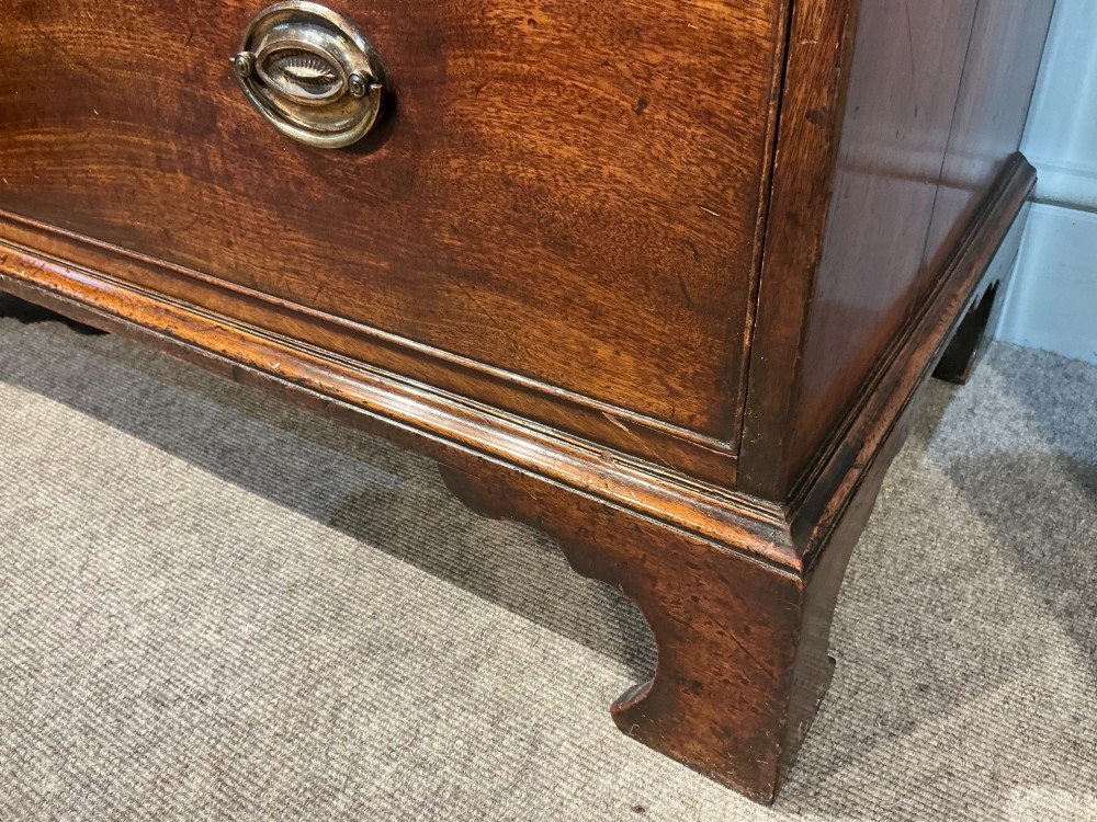 A Georgian mahogany chest of drawers with three graduated drawers, oval brass drop handles, and bracket feet. View IV