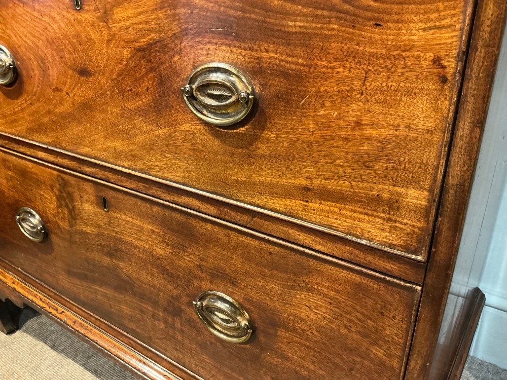 A Georgian mahogany chest of drawers with three graduated drawers, oval brass drop handles, and bracket feet. View V