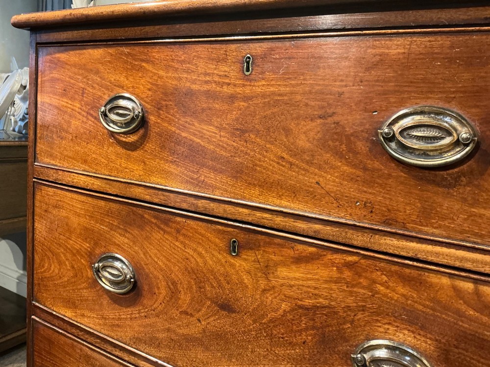 A Georgian mahogany chest of drawers with three graduated drawers, oval brass drop handles, and bracket feet. View VI