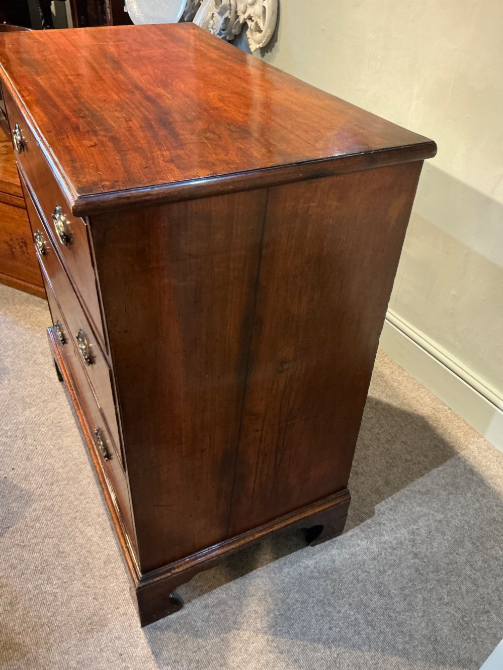 A Georgian mahogany chest of drawers with three graduated drawers, oval brass drop handles, and bracket feet. View IX