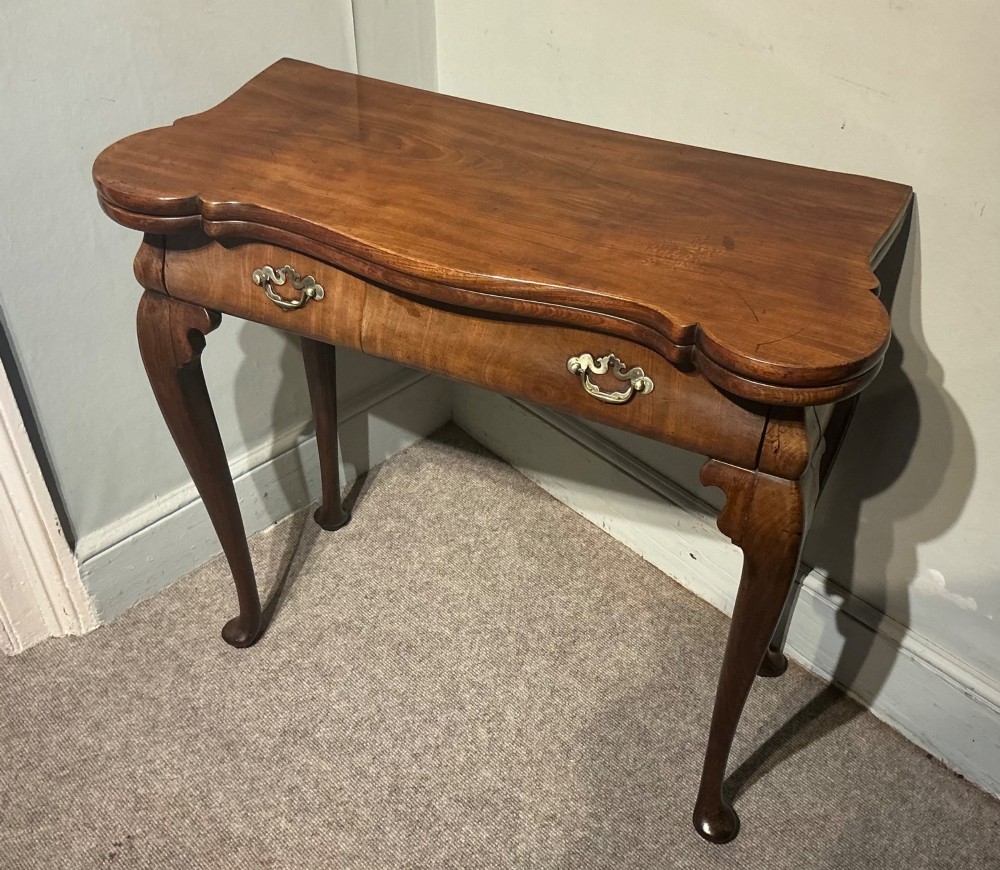 A Georgian walnut folding card table featuring a serpentine front, cabriole legs with pad feet, and brass handles. View II