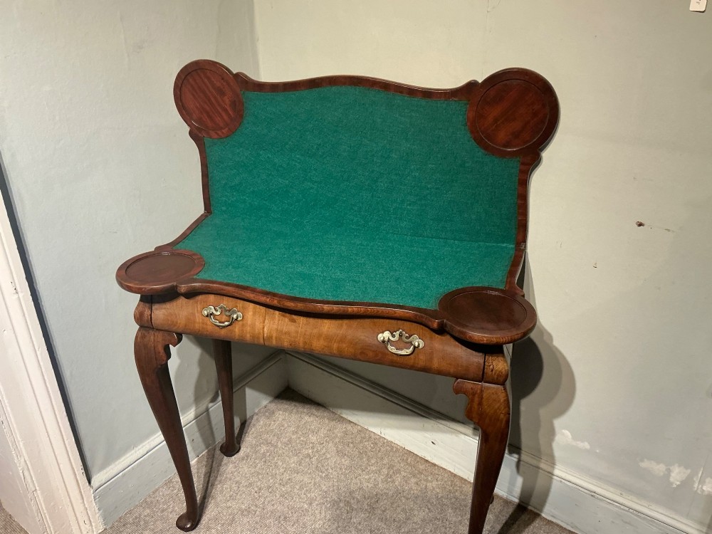 A Georgian walnut folding card table featuring a serpentine front, cabriole legs with pad feet, and brass handles. View III