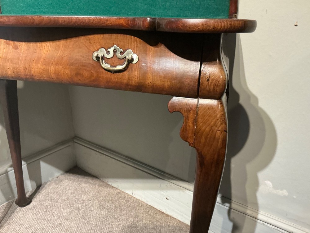 A Georgian walnut folding card table featuring a serpentine front, cabriole legs with pad feet, and brass handles. View IV