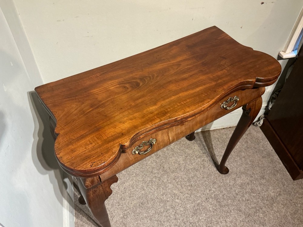 A Georgian walnut folding card table featuring a serpentine front, cabriole legs with pad feet, and brass handles. View V