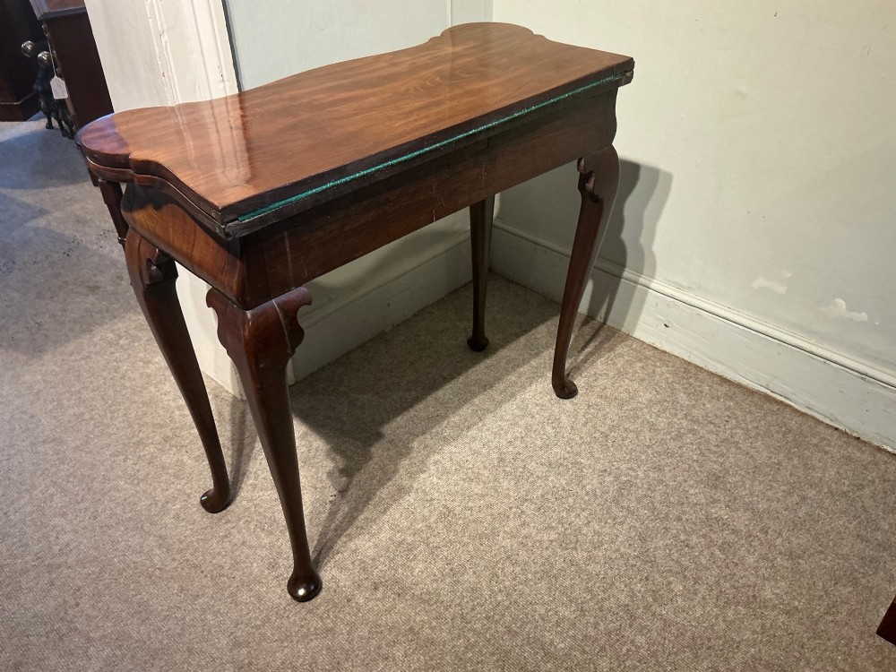 A Georgian walnut folding card table featuring a serpentine front, cabriole legs with pad feet, and brass handles. View VII