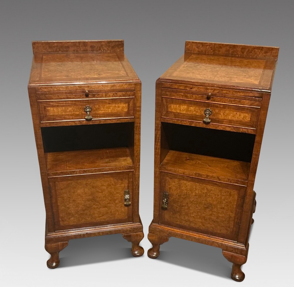 A matching pair of burr walnut bedside cabinets featuring pull-out slides, single drawers, open cubbies, lower cupboard doors, and cabriole legs.