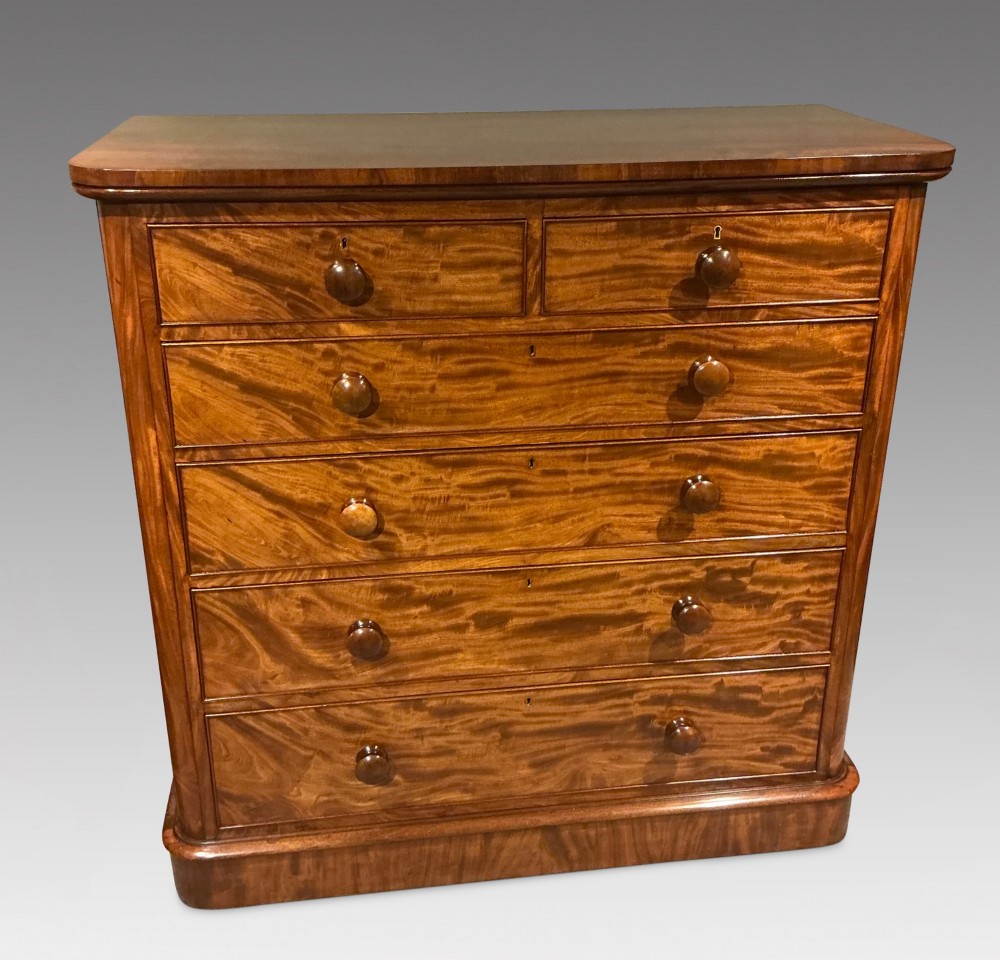 A Victorian mahogany chest of drawers featuring two short drawers over three long drawers with turned wooden knobs and flame veneer fronts.