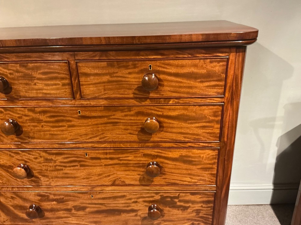 A Victorian mahogany chest of drawers featuring two short drawers over three long drawers with turned wooden knobs and flame veneer fronts. View III