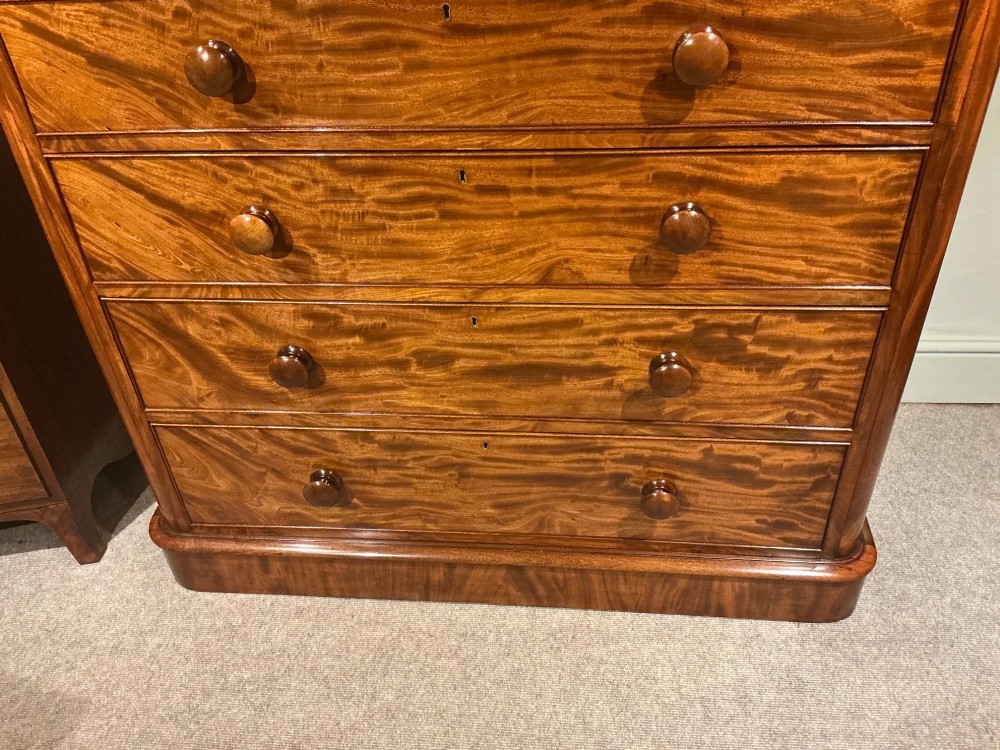 A Victorian mahogany chest of drawers featuring two short drawers over three long drawers with turned wooden knobs and flame veneer fronts. View V